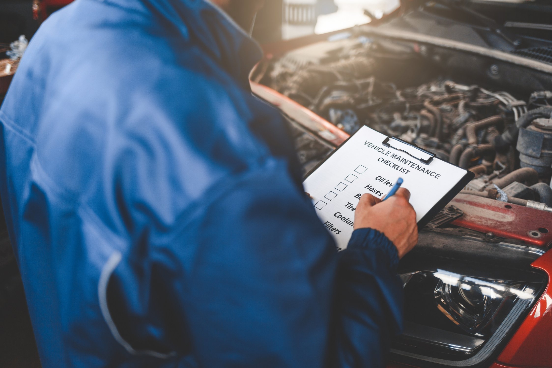 Mechanic Inspecting the Car with Checklist on Clipboard